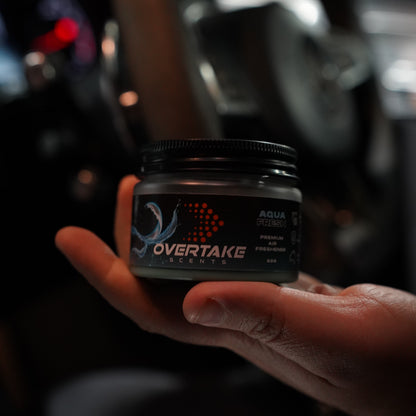 Aqua Fresh gel car air freshener resting in open palm, dark moody garage setting — Overtake Scents