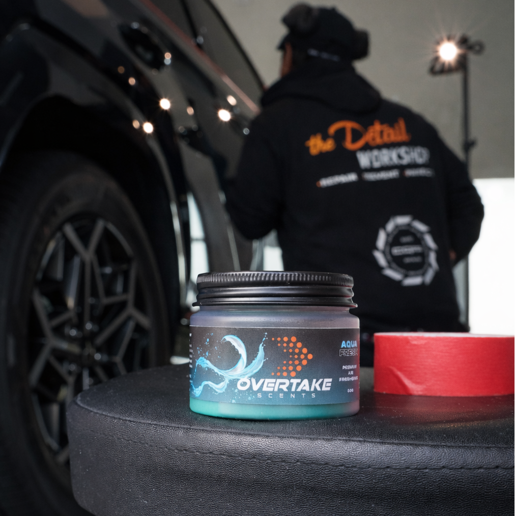 Aqua Fresh gel car air freshener at The Detail Workshop car detailing studio, detailer working on black vehicle in background — Overtake Scents