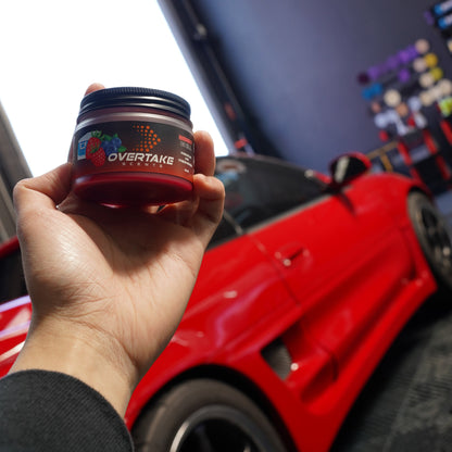 Berry Chill gel car air freshener held in hand with red Toyota MR2 in background at car garage — Overtake Scents