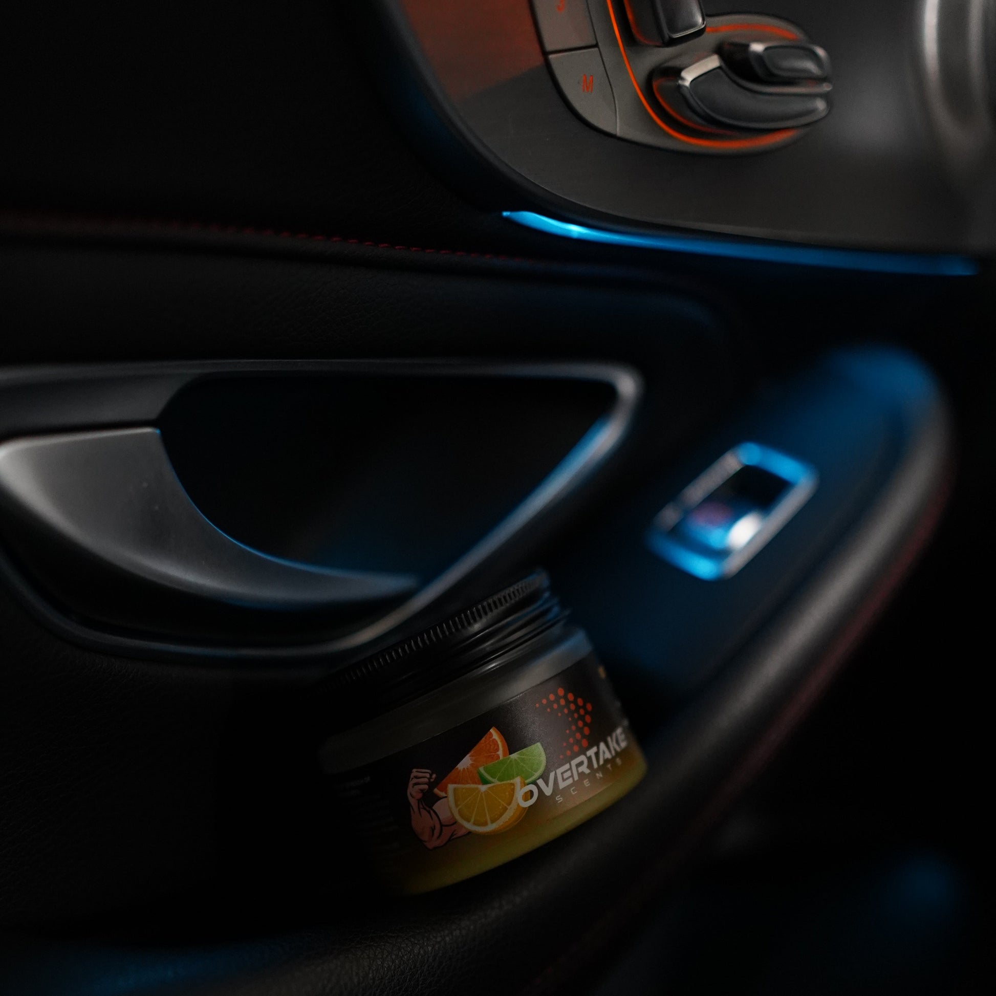 Citrus Lift gel car air freshener in car door storage pocket with blue ambient lighting — Overtake Scents