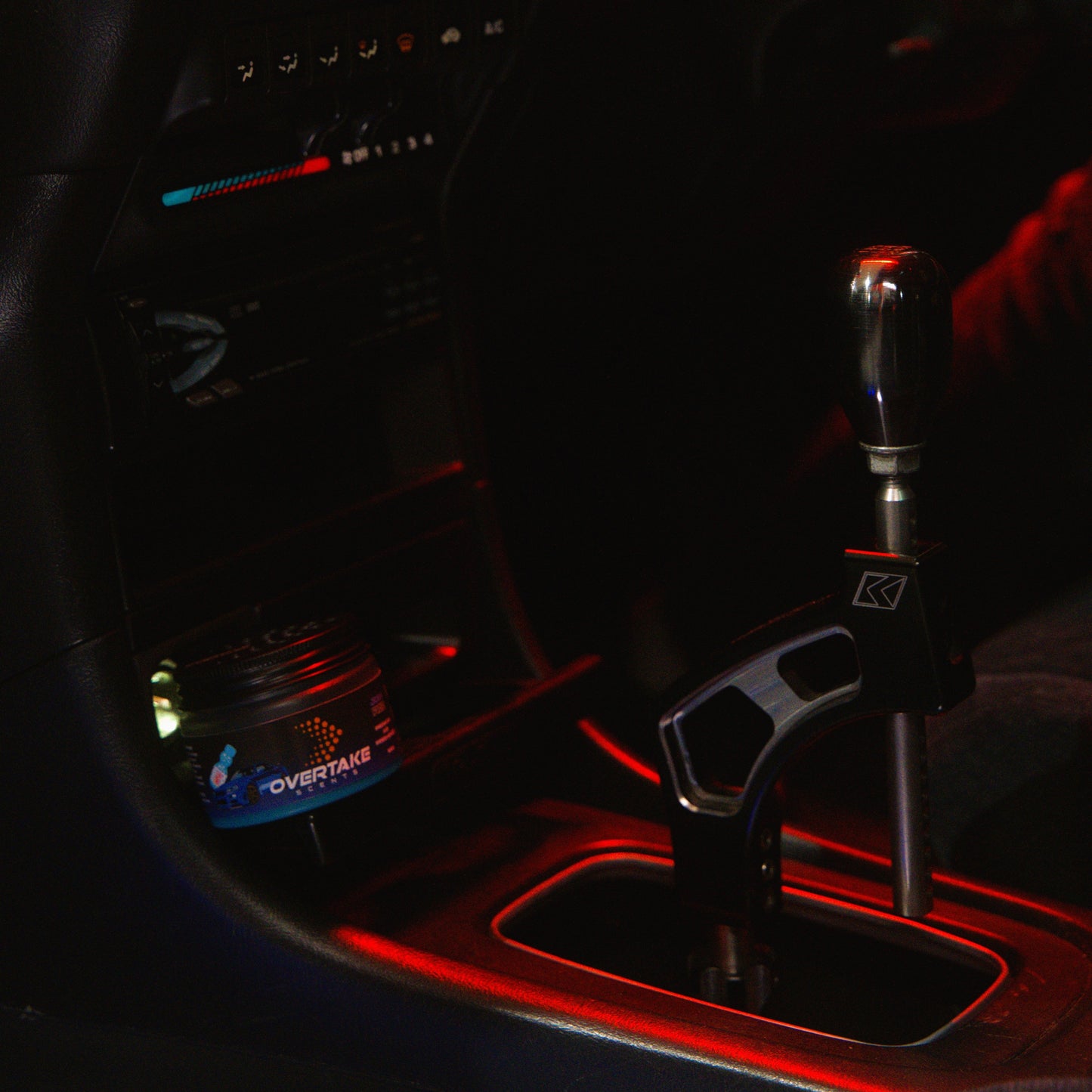 JDM Fizz gel car air freshener next to short-throw shifter in car interior with red ambient lighting — Overtake Scents