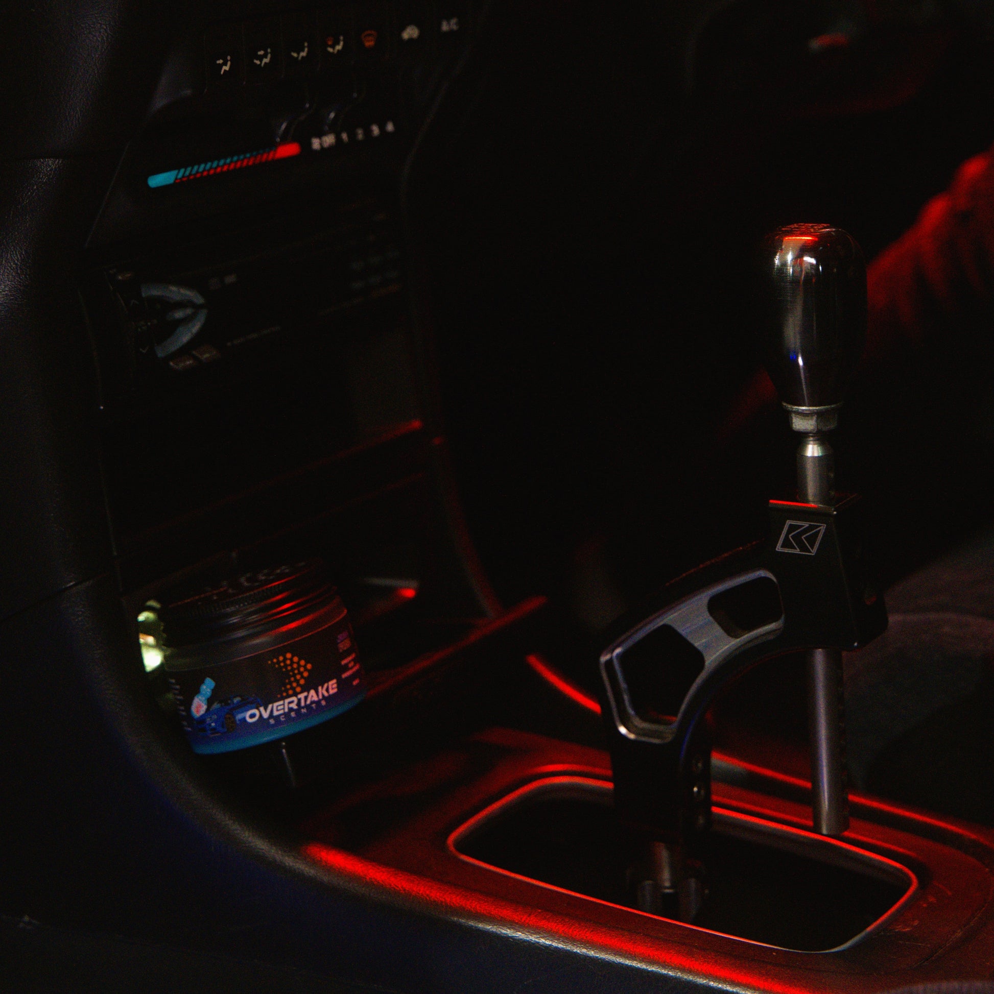 JDM Fizz gel car air freshener next to short-throw shifter in car interior with red ambient lighting — Overtake Scents
